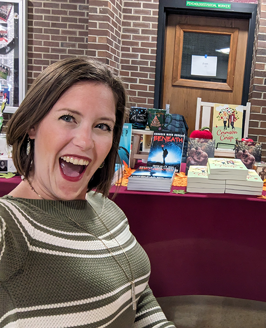 Woman with short brown hair sitting in front of a table with books on it