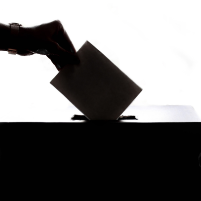 Silhouette of a hand dropping a ballot into a box