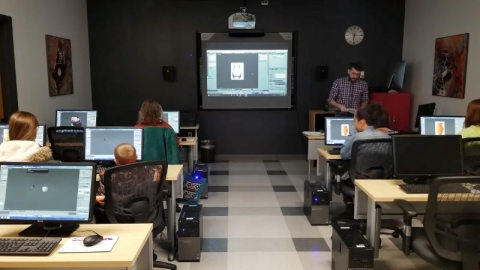 Photo from class with library instructor demonstrating blending in image editing software to a group of students at computer stations