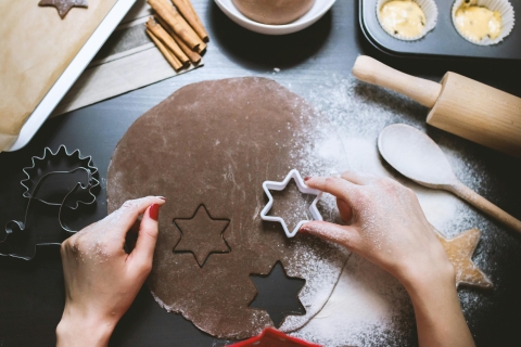 Hands are shown cutting dough with a cookie cutter