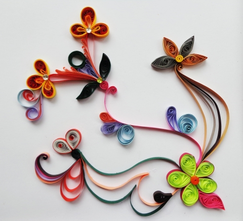 white page with colorful paper quill flowers laid out in an flowy design