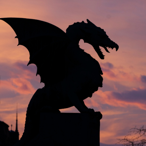 silhouette of a dragon against a pink and purple sky