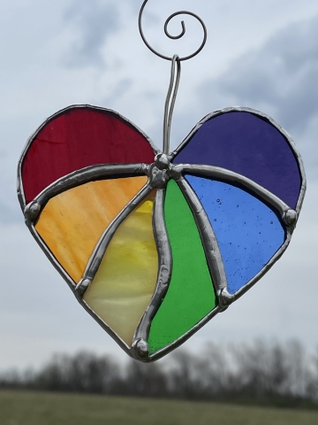 a heart made of stained glass soldered together with triangular sections of different colors in the colors of the rainbow