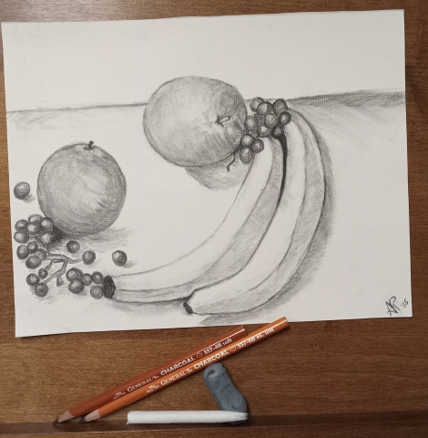 Charcoal drawing of apples, bananas and grapes with charcoal pencils, eraser and smudge stick.