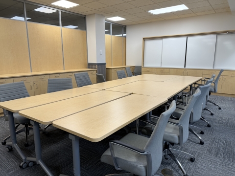 room with 9 tables joined together in a conference room configuration with 12 chairs