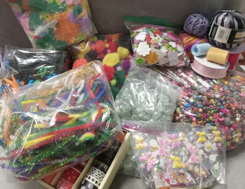 Bags of colorful feathers, beads, pom-poms, stickers, marbles, pipe cleaners and ribbon.