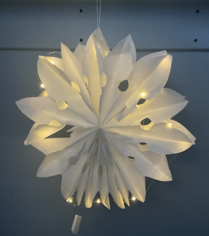 White paper cut-out snowflake illuminated with mini LED Fairy lights