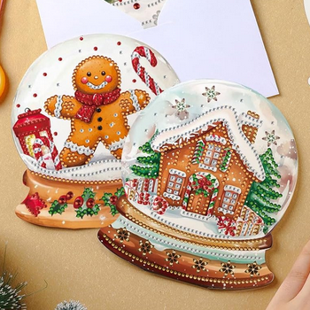 Two completed diamond art snow globe holiday cards, a snowy house and a gingerbread man.