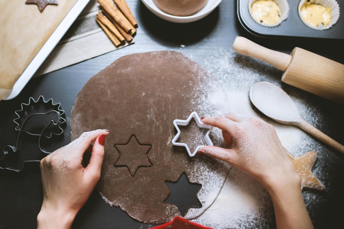 Hands are shown cutting dough with a cookie cutter