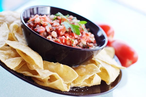 salsa in a black bowl surrounded by tortilla chips