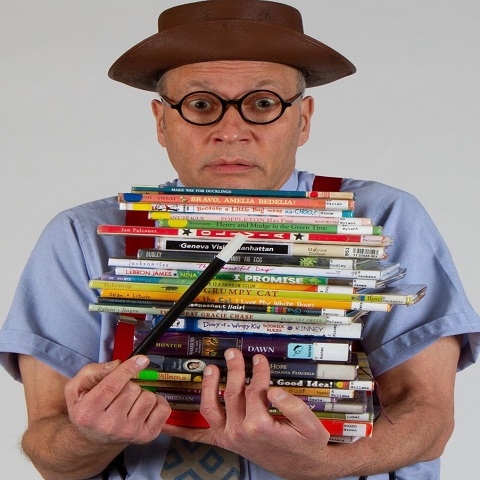 Picture of a man holding a stack of children's books.