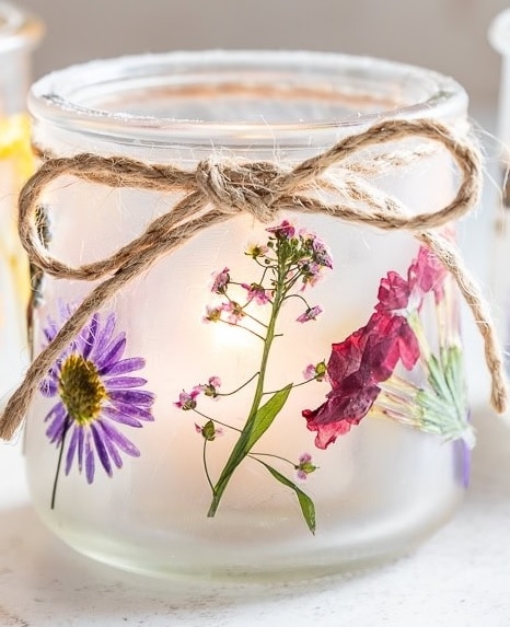 Close-up of a small frosted jar with attached flowers and a string bow.