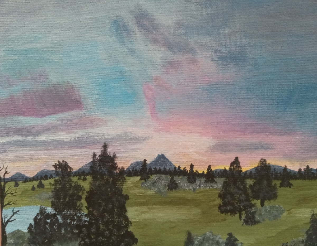 Pink and purple sunset sky over golf course with mountains in the background.