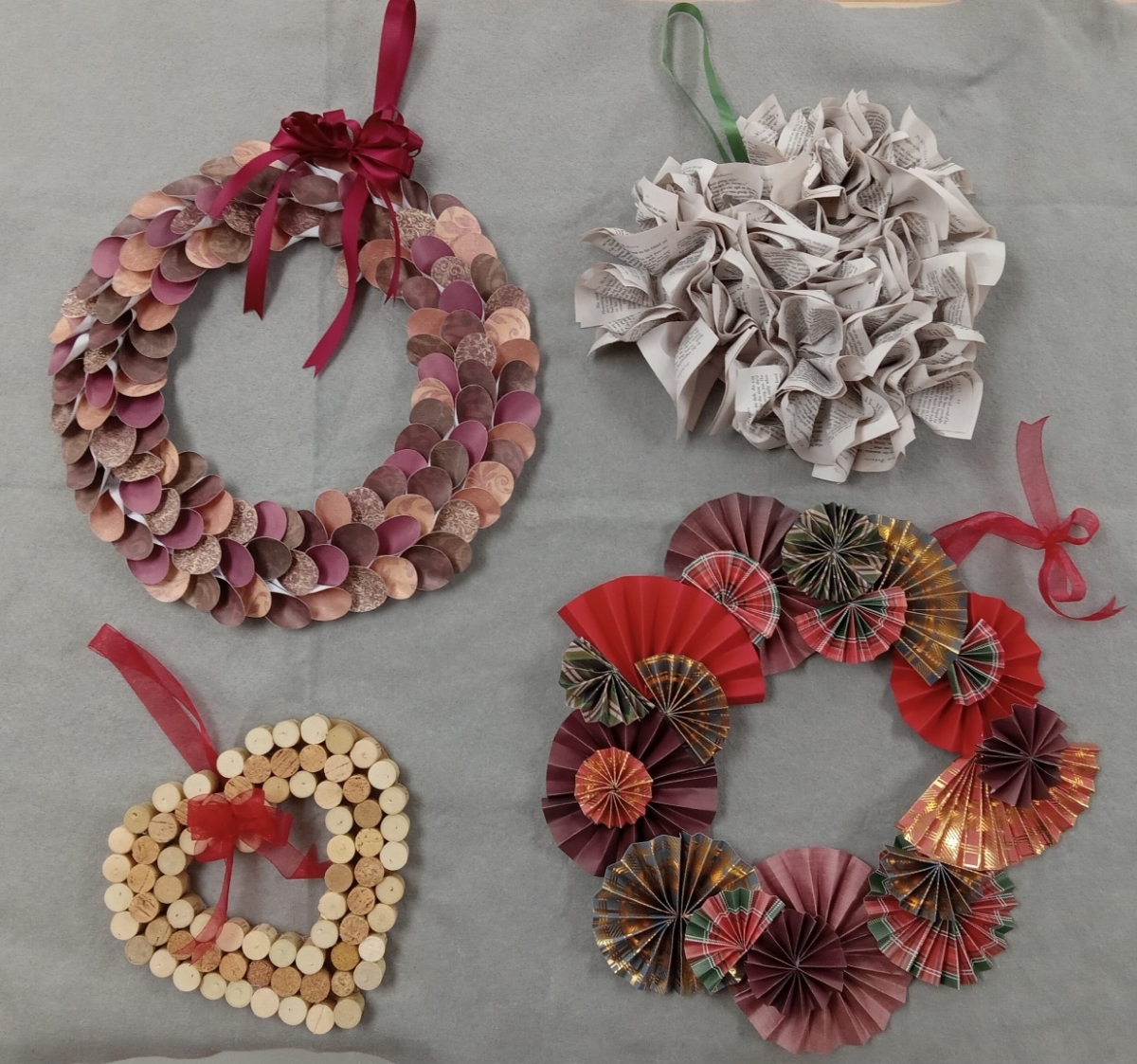 Four wreaths made with paper and wine corks and ribbon hangers.