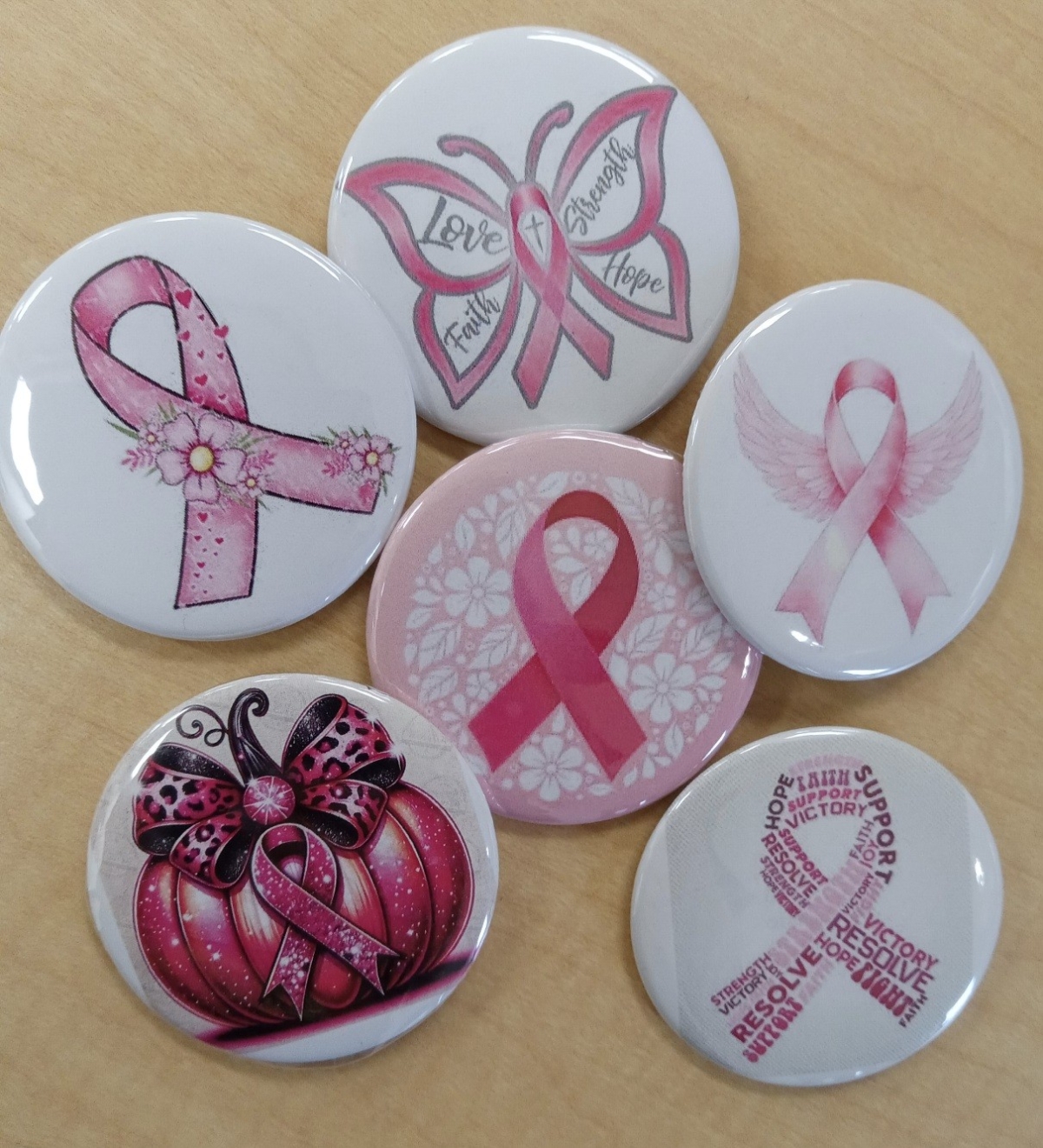 Six buttons with pink ribbons denoting breast cancer awareness.