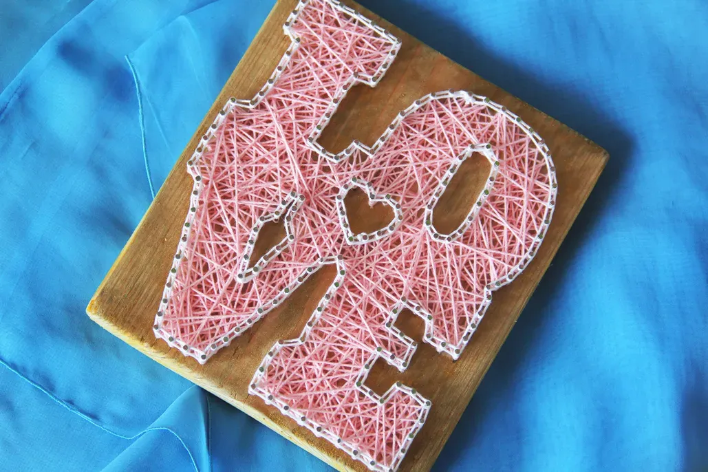 The word Love done in pink string art