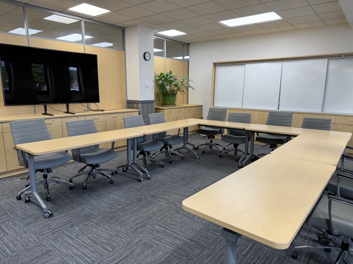 room with tables, chairs, and large monitor