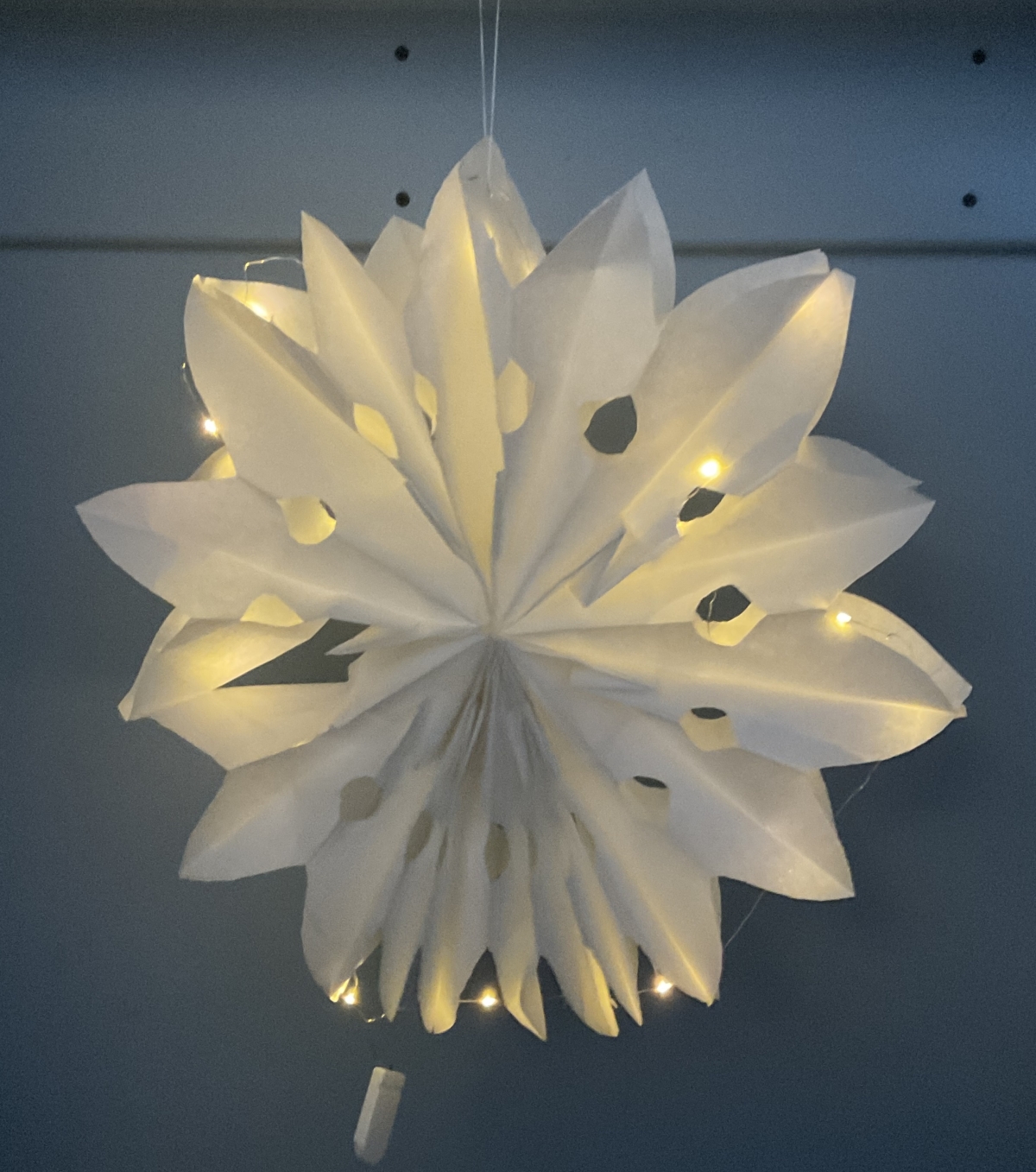 White paper cut-out snowflake illuminated with mini LED Fairy lights