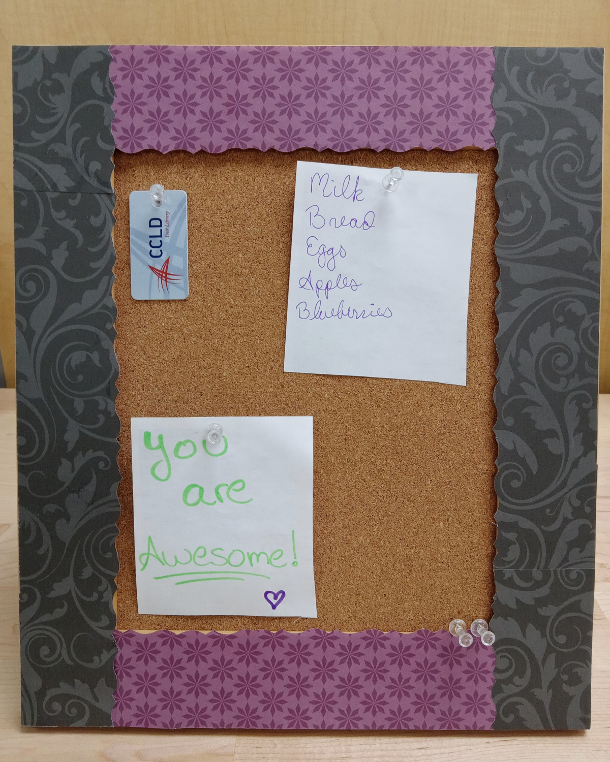 Black and purple framed cork board